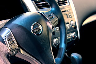 person taking photo of black Nissan steering wheel