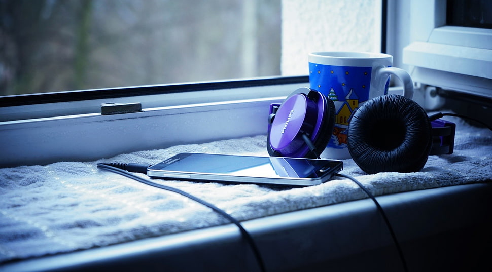 black and purple headphones beside ceramic mug near window pane HD wallpaper