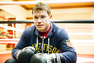 man in gray hooded jacket with boxing gloves inside the gym