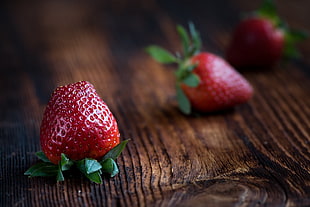close up photography of red strawberry on brown wooden surface