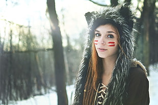 woman in black fur-trim hooded jacket with red paint on face
