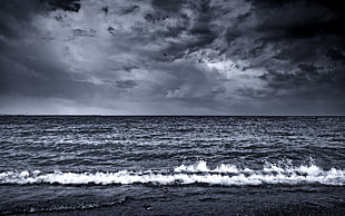 gray scale photo of body of water under cloudy sky