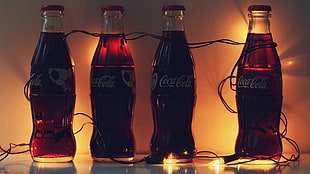 four coca cola bottled on table