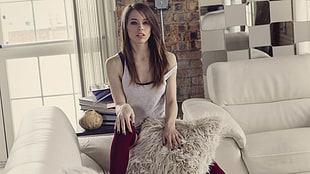 woman in white tank top holding fur pillow