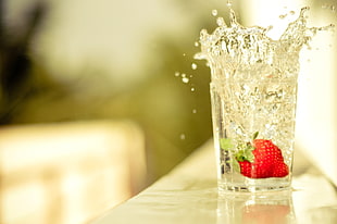 photography of sinked strawberry fruit on clear drinking glass filled with water