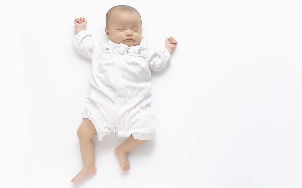 baby in white shirt lying on white surface HD wallpaper