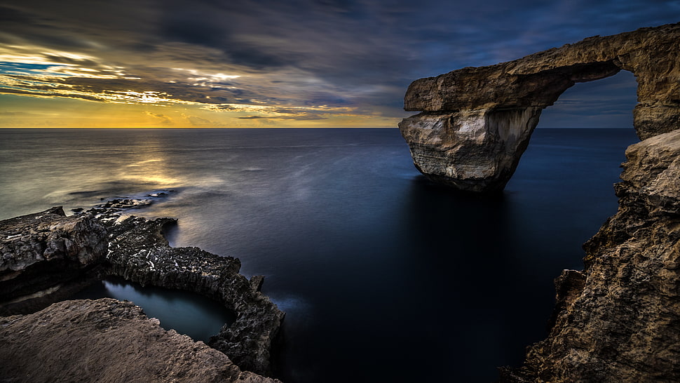 brown and black stone formation on water HD wallpaper