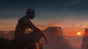 man sitting on rock formation during golden hour