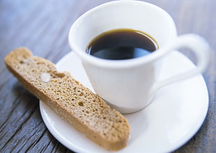 brown bread beside white ceramic cup with black liquid inside