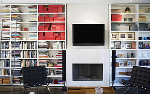wall mount black flat screen television over fireplace center of book shelves