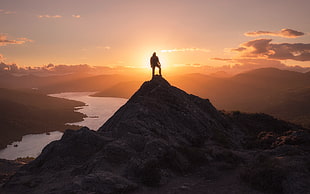 man standing on tip of mountain during golden hour