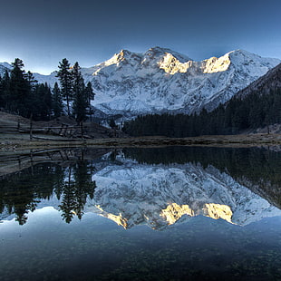 mountain with snow near body of water