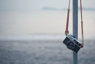 grey and black SLR camera hanging on grey pole