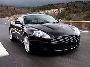 Time Lapse photography of black Aston Martin coupe crossing road during daytime