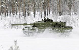 green armored tank running on snow field