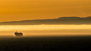 black ship on sea during yellow sunset HD wallpaper