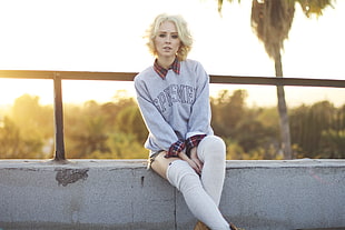 woman in gray sweater sitting on concrete bench