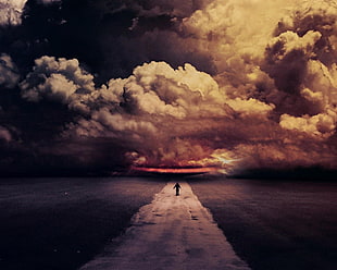 person standing on road under white clouds