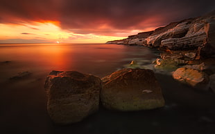 time-lapse photography of cliff beside ocean during golden hour