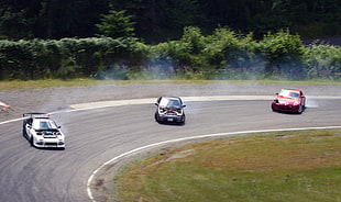 three racing cars on road during daytime