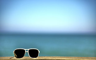 white-framed sunglasses on white cement