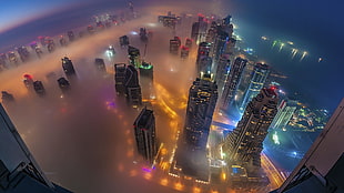 high-rise buildings surrounded with fogs at nighttime