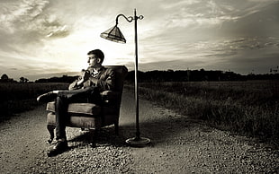 grayscale photo of man sitting on chair