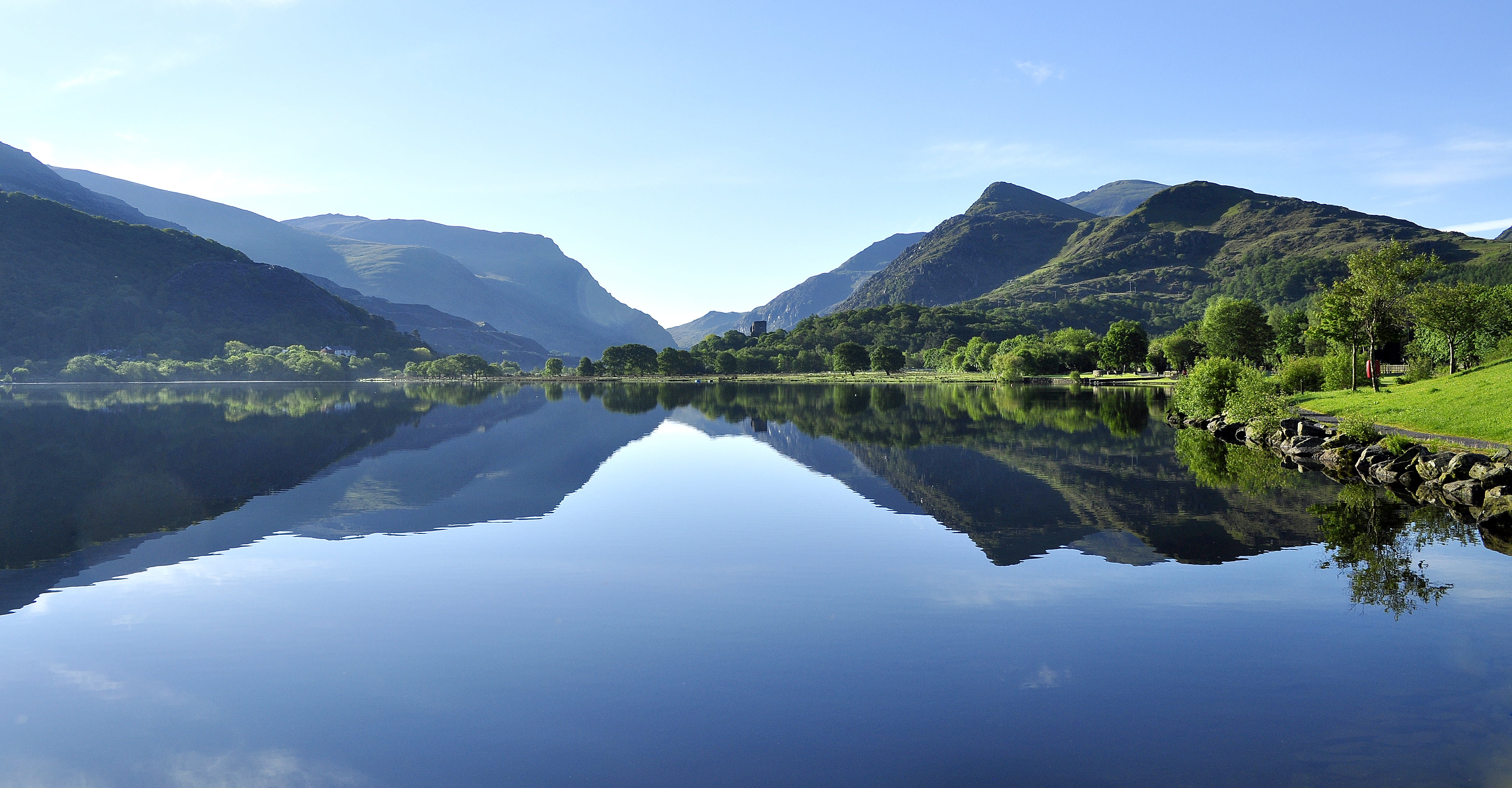 landscape photography of lake near green leaf trees under clear sky