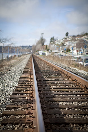 photo of rusty brown metal train rail, white rock
