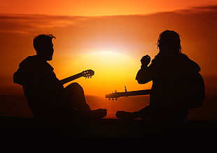 silhouette of  two person playing guitars during sunset