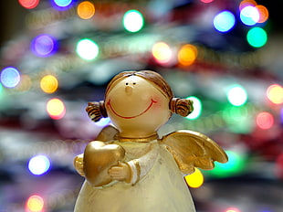 bokeh photography of white and gold-colored angel figurine