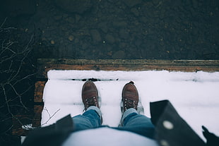 high-angle photography of person standing on snow-coated brown wooden dock