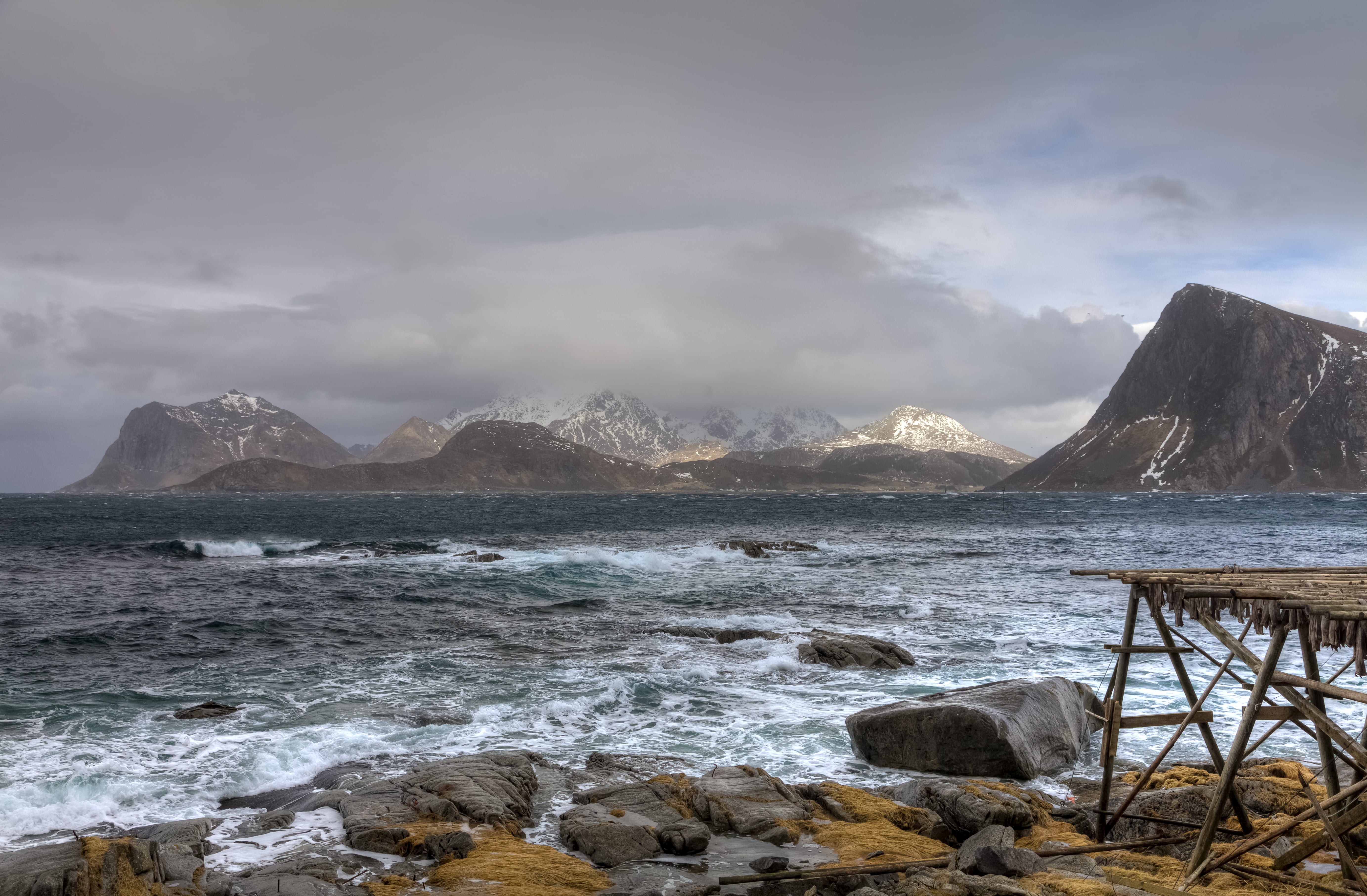 rocky seashore in front of gray mountains and clouds during daytime