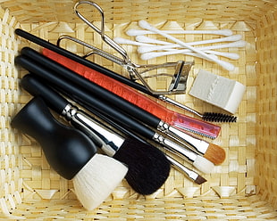 assorted makeup brushes on brown wicker basket