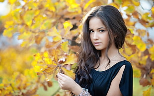 woman in black top holding yellow leaf