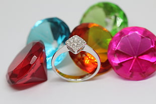 colored gemstones beside silver ring