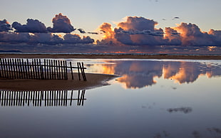 body of water under white cloudy sky during yellow sunset