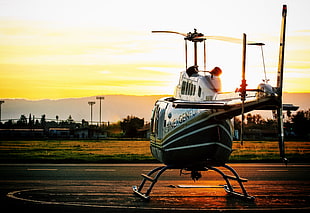 green and white helicopter during sunset
