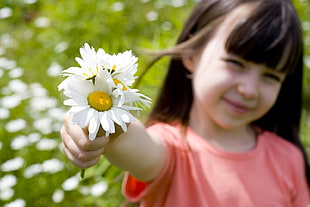 girl holding white petaled flower