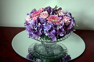purple and pink flower bouquet on clear footed vase