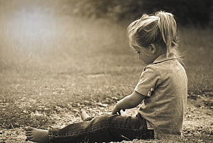 girl with gray polo shirt with black denim jeans sitting on grass field at daytime