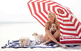 woman sit on sand beside tree puppies