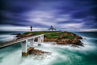 slow shutter photography of bridge near townhouse with lighthouse