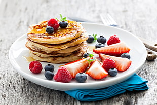 pancake with honey and strawberries on white ceramic plate