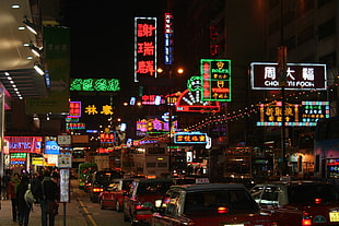 vehicles on road near people walking on side walk and buildings with neon signage, Hong Kong, night, urban, traffic