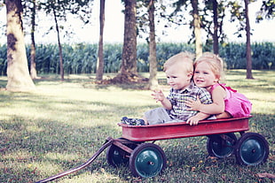 boy and girl riding on a red wagon