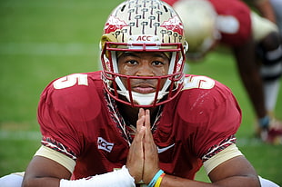 football player wearing helmet doing prayer gesture