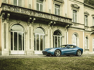blue coupe parked near beige concrete mansion at daytime