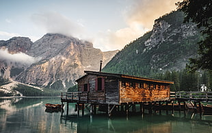 brown wooden house on body of water near mountian