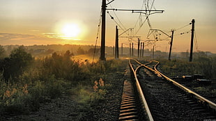 sunset photo of train railway near road lights